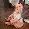 baby, child, tutu, bow, headband, balloon, floor, wooden_floor, shoe, pink, white_shirt, sitting, curious, indoor, cute, chubby_cheeks, person, infant, party, celebration