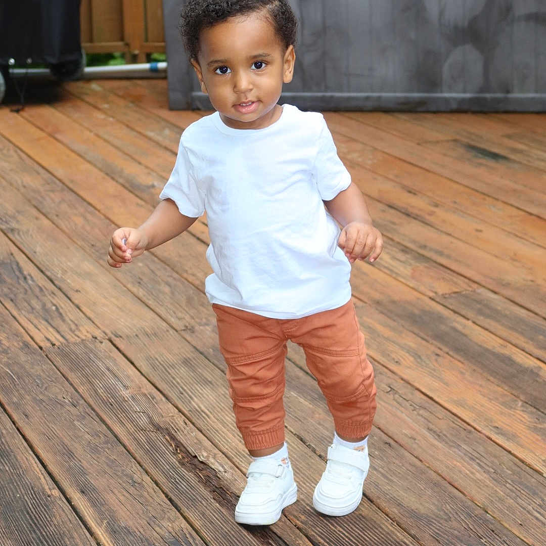 Winston joined the competition — help win amazing prizes! toddler, child, white_tshirt, orange_pants, white_sneakers, wooden_deck, outdoor, walking, curly_hair, smiling, person, young_child, cute, casual_clothing, daylight, standing, portrait, happy, small_child, fun