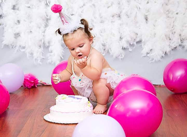 Masaya is registered to the contest to win money with this photo: arm, baby, baby_toddler_clothing, balloon, beauty, child, dress, event, facial_expression, fun, happy, hat, headpiece, magenta, party_supply, person, pink, sugar_cake, table, toddler