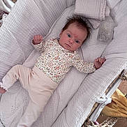 Evelyn joined the competition — help win amazing prizes! baby, infant, bassinet, blanket, bottle, clothing, cute, expression, face, floral_pattern, footwear, furniture, hair, indoor, laying_down, person, pink_pants, soft_texture, wood_floor, white