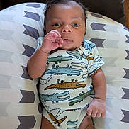Sebastian joined the competition — help win amazing prizes! baby, infant, onesie, crocodile_pattern, pillow, geometric_pattern, hand, face, skin, clothing, cute, lying_down, indoors, child, newborn, person, resting, comfortable, expression, young