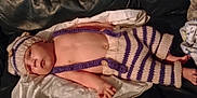 Rylan is registered to the contest to win money with this photo: baby, infant, knitted_clothing, hat, striped, couch, blanket, soft, relaxed, indoors, child, person, cute, warm, resting, handmade, comfortable, skin, lying_down, apparel