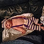 baby, infant, knitted_clothing, hat, striped, couch, blanket, soft, relaxed, indoors, child, person, cute, warm, resting, handmade, comfortable, skin, lying_down, apparel