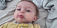 Christian joined the competition — help win amazing prizes! baby, child, pout, yellow_stripes, onesie, bed, blanket, clothing, face, person, infant, rumpled_bed, lying_down, cute, expression, indoors, toddler, sleepwear, soft_lighting, casual