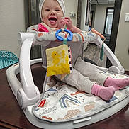 Jamie Lynn joined the competition — help win amazing prizes! baby, smiling, towel, walker, toy, table, indoor, child, pink_socks, pants, happy, face, headwear, playtime, seated, home, furniture, colorful, person, cute