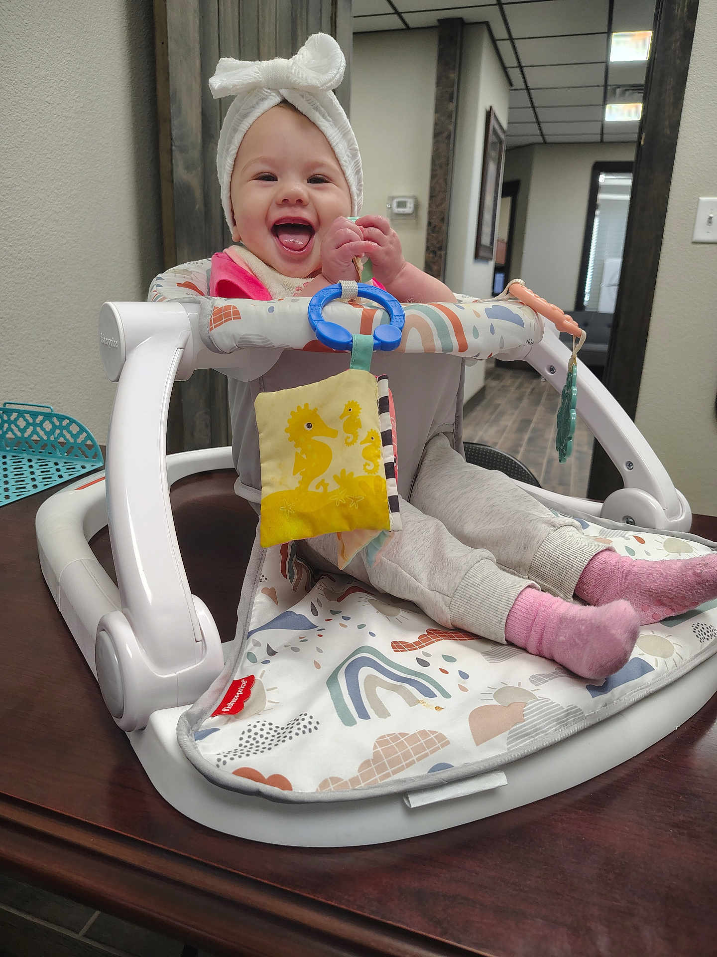 Jamie Lynn joined the competition — help win amazing prizes! baby, smiling, towel, walker, toy, table, indoor, child, pink_socks, pants, happy, face, headwear, playtime, seated, home, furniture, colorful, person, cute