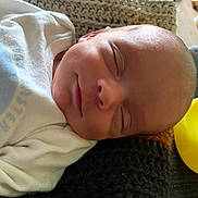 Bryer is registered to the contest to win money with this photo: newborn, baby, sleeping, rubber_duck, knitted_blanket, white_outfit, bunny_design, cozy, peaceful, infant, face, head, portrait, child, soft_lighting, cute, resting, indoors, closeup, smile
