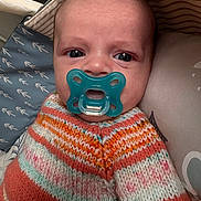 Tim a rejoint le concours — aidez-le/la à gagner de superbes lots ! baby, pacifier, knitted_sweater, close_up, infant, face, blue_pacifier, patterned_cushion, child, cute, portrait, indoors, young_child, sitting, colorful_clothing, soft_lighting, newborn, baby_face, couch, resting