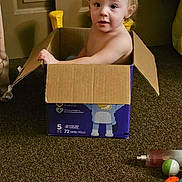 Jordan joined the competition — help win amazing prizes! toddler, child, cardboard_box, indoor, carpet, toy, diaper, curious, looking_up, floor, brown, door, plastic_toy, container, young_child, playtime, room, casual, home, person