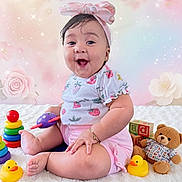 Paulette is registered to the contest to win money with this photo: baby, child, smiling, pink_bow, headband, strawberry_pattern, toy, rubber_duck, teddy_bear, stacking_rings, pastel_background, floral, sparkles, white_blanket, cute, happy, sitting, bracelet, shorts, playtime