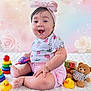 baby, child, smiling, pink_bow, headband, strawberry_pattern, toy, rubber_duck, teddy_bear, stacking_rings, pastel_background, floral, sparkles, white_blanket, cute, happy, sitting, bracelet, shorts, playtime