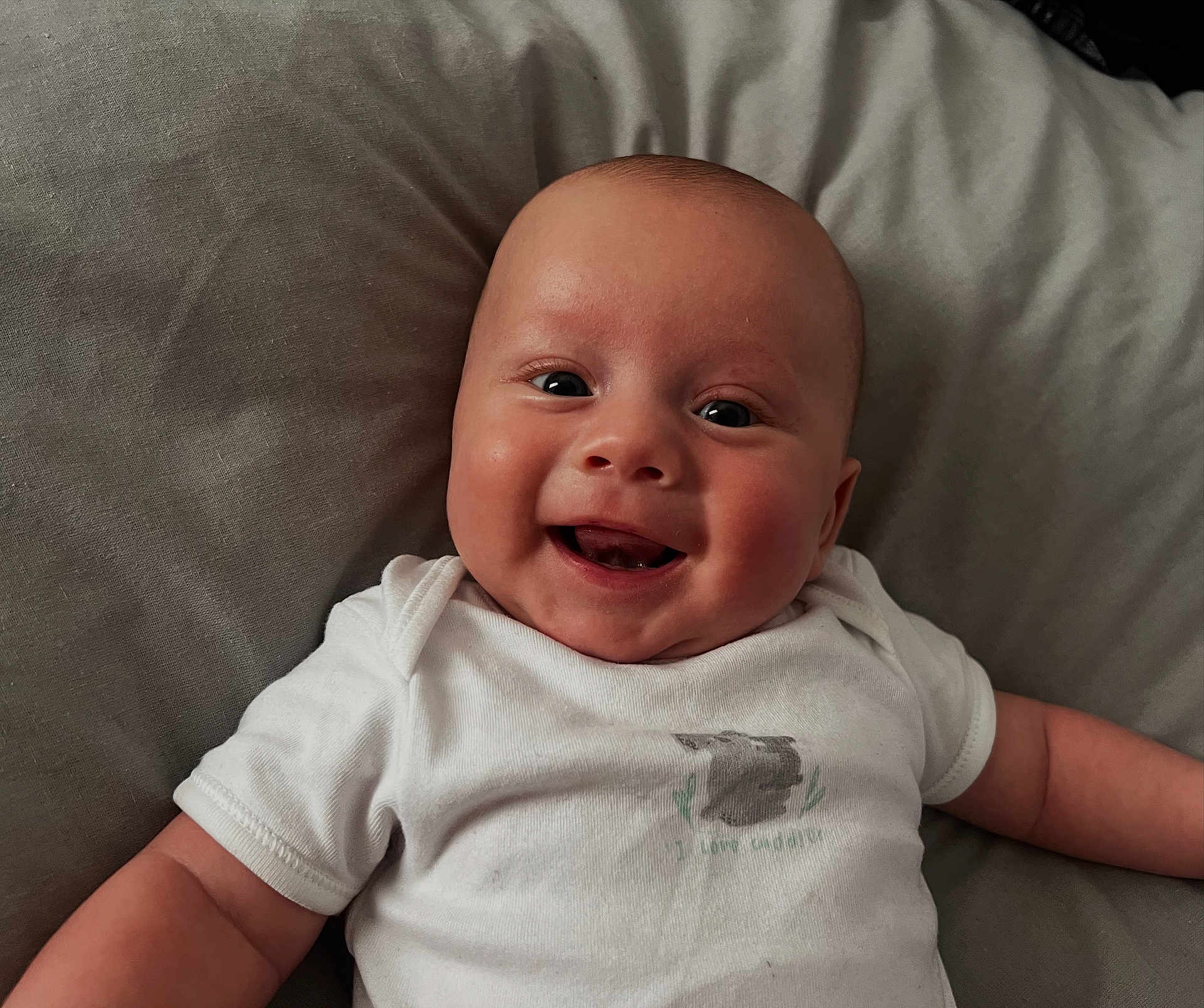 Lucas joined the competition — help win amazing prizes! baby, smiling, infant, onesie, white_clothing, happy, face, cute, child, lying_down, soft_surface, closeup, skin, head, cheeks, eyes, arms, casual, indoor, portrait