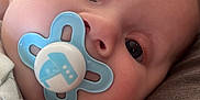 Lucas is registered to the contest to win money with this photo: baby, blue, child, close_up, clothing, comfort, cute, eyes, face, hand, infant, innocence, lying_down, mouth, nose, pacifier, skin, sleepy, soft, young