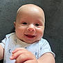 Lucas is registered to the contest to win money with this photo: baby, background, child, closeup, clothing, cute, expression, fabric, face, hand, happy, indoor, infant, lying_down, onesie, person, portrait, skin, smiling, young