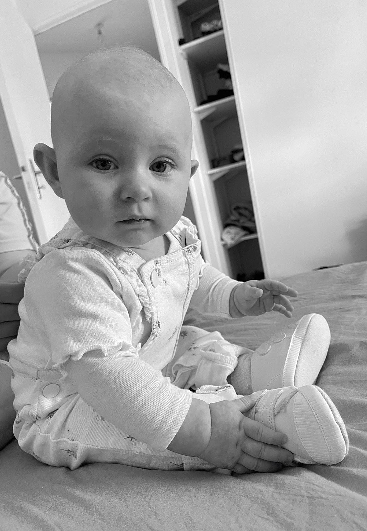 Thaïna participe au concours pour gagner de l'argent avec cette photo : baby, baby_toddler_clothing, black_and_white, cheek, child, comfort, flooring, foot, fun, happy, human_leg, knee, leg, monochrome, monochrome_photography, person, room, sitting, standing, style