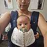 Onyx joined the competition — help win amazing prizes! baby, person, glasses, pacifier, bib, baby_carrier, indoor, home, portrait, wearing, face, child, holding, modern_art, wall_art, casual, clothing, expression, front_view, parent