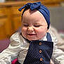 baby, smiling, headband, blue, polka_dot, outfit, white_shirt, happy, cute, infant, portrait, indoor, child, clothing, button, face, person, soft_focus, blurry_background, joyful