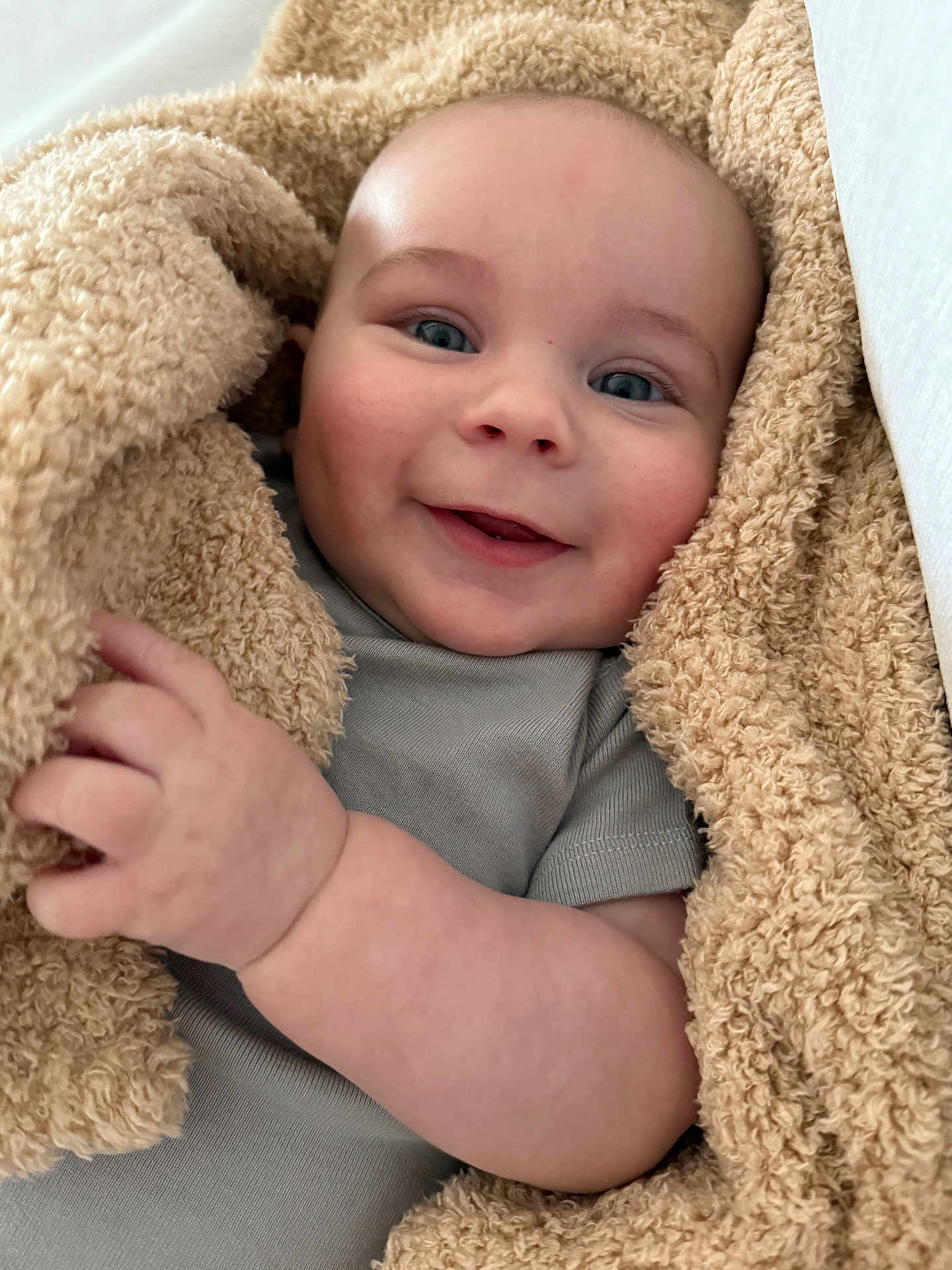 Daniel joined the competition — help win amazing prizes! baby, infant, smiling, blanket, cozy, closeup, portrait, hand, blue_eyes, onesie, fabric, skin, cheeks, adorable, soft_texture, wrap, bed, cuteness, happy, burrito_wrap