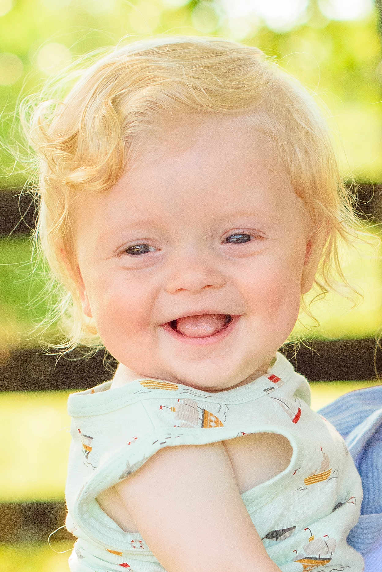 Kolton is registered to the contest to win money with this photo: child, toddler, smiling, blond_hair, curly_hair, shirt, sleeveless, outdoor, daylight, happy, portrait, face, skin, baby, cute, nature, greenery, background, expression, person