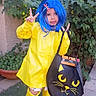 child, blue_wig, yellow_raincoat, yellow_boots, peace_sign, black_bag, cat_face, outdoor, greenery, grass, playful, costume, butterfly_clip, smiling, person, portrait, garden, sidewalk, nature, cute