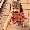 child, cute, daylight, face, floral_skirt, hair_tie, happy, holding_hands, outdoor, pavement, person, pink_clothing, sidewalk, skin, small_hands, smiling, sunlight, toddler, walking, white_shoes