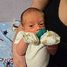 Luis is registered to the contest to win money with this photo: baby, infant, pacifier, mittens, bear_pattern, arm, hand, person, blanket, blue_blanket, dog_pattern, star_pattern, clothing, white_onesie, indoor, portrait, cute, newborn, resting, closeup