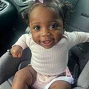 Armani is registered to the contest to win money with this photo: baby, child, smiling, car_seat, pink_bow, pink_clothing, infant, happy, cute, portrait, indoors, seatbelt, toddler, person, face, hair, skin, clothing, car_interior, sitting