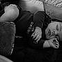 baby, sleeping, infant, blanket, crib, black_and_white, hand, face, clothing, soft_texture, peaceful, resting, child, cute, newborn, portrait, indoors, cozy, toddler, furniture