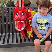 Kaique Bbc participe au concours pour gagner de l'argent avec cette photo : bench, boy, casual, chairs, child, concrete, daytime, dragon_puppet, outdoor, people, plants, playful, public_space, sandals, shorts, smiling, table, toy, tshirt, urban