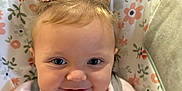 Nina is registered to the contest to win money with this photo: baby, baby_seat, child, close_up, cute, face, floral_pattern, hair_bows, happy, indoors, infant, person, pink_clothing, portrait, seatbelt, small_hair_ties, smiling, soft_lighting, toddler, young_child
