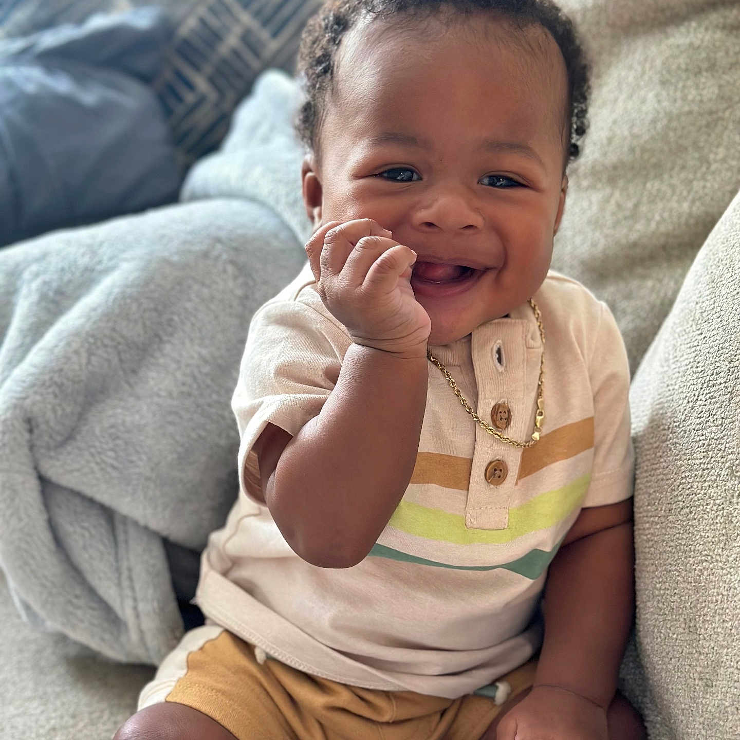 Symere joined the competition — help win amazing prizes! baby, child, clothing, couch, cozy, curly_hair, cute, face, footwear, gold_chain, hand, happy, indoor, person, portrait, shirt, shorts, sitting, skin, smiling