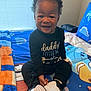 Symere joined the competition — help win amazing prizes! baby, child, smiling, sitting, indoor, bed, blanket, window, curtain, clothing, shoes, footwear, person, face, happy, cute, hair, toy, pattern, colorful