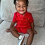 toddler, child, smiling, red_clothing, polo_shirt, shorts, checkered_shoes, sitting, couch, indoor, happy, cute, person, footwear, curly_hair, comfortable, portrait, infant, skin, young