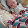 baby, blanket, clothing, colorful, comfort, cozy, cushion, expression, face, geometric_pattern, head, indoors, infant, pattern, portrait, resting, seat, skin, soft_texture, young_child