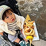 Kei participe au concours pour gagner de l'argent avec cette photo : toddler, child, stroller, cap, striped_shirt, white_jacket, shoes, fried_seafood, shrimp, calamari, lemon, hand, street_food, pavement, outdoor, curious, food_cone, casual_clothing, snack, daytime