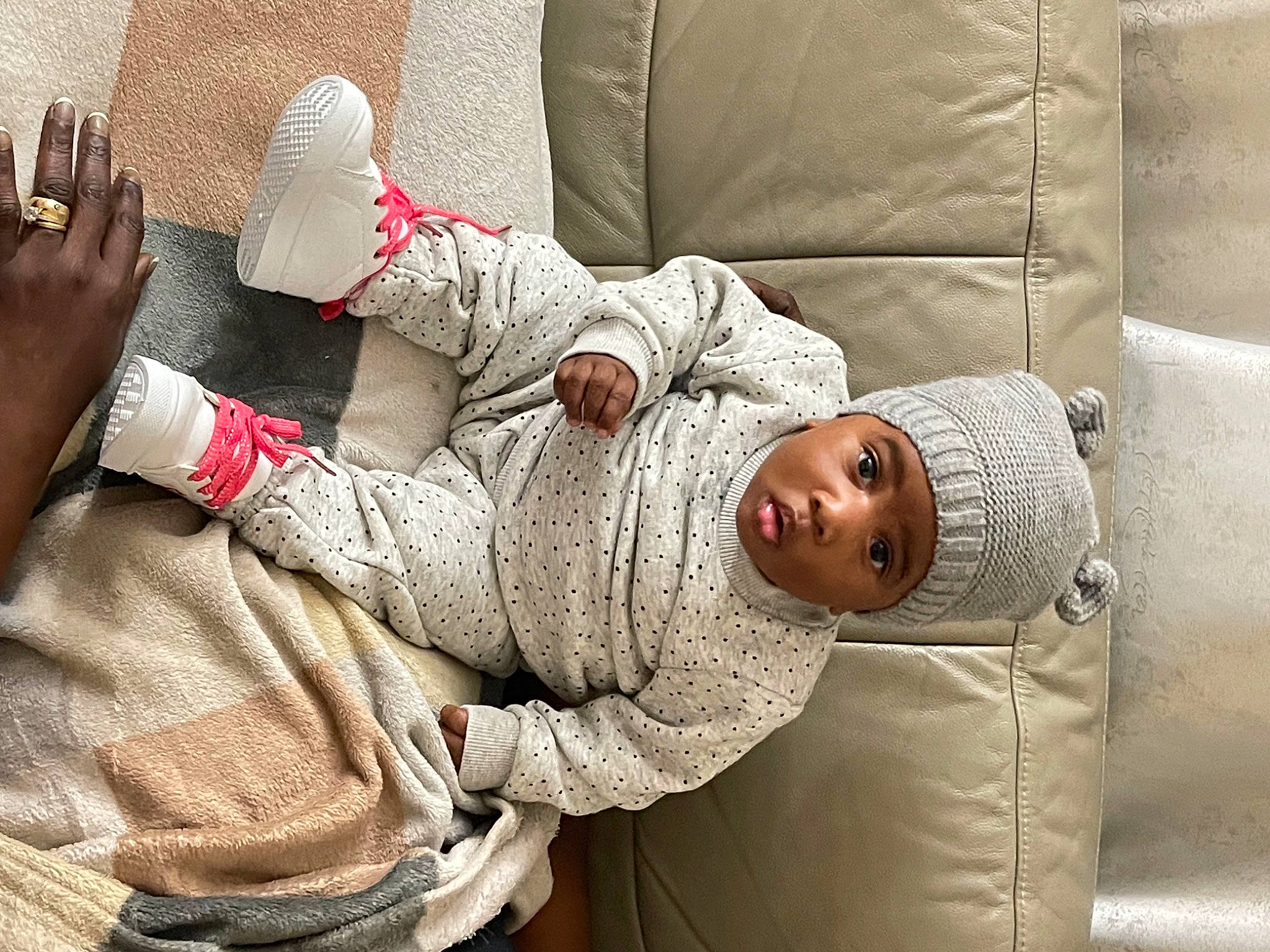 Lyannah participe au concours pour gagner de l'argent avec cette photo : arm, baby, child, comfort, couch, elbow, finger, gesture, grey, hand, headwear, human_body, human_leg, joint, leg, linens, person, room, sitting, sleeve