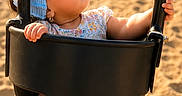Camila is registered to the contest to win money with this photo: baby, black_swing, blue_bonnet, child, curious, cute, daylight, footwearless, grass, infant, outdoor, park, person, play, playground, sand, summer, sunlight, swing, toddler