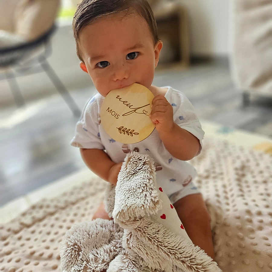 Taïan a rejoint le concours — aidez-le/la à gagner de superbes lots ! baby, blanket, blurred_background, child, comfort, cute, face, feet, floor, hands, home, indoor, infant, milestone_marker, nibbling, plush_toy, short_sleeve, sitting, soft_toy, wooden_milestone