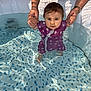 toddler, baby, child, swimsuit, water, pool, adult_hands, sunlight, reflection, outdoor, playing, summer, splash, holding_hands, purple_clothing, polka_dot, cute, face, feet, fun
