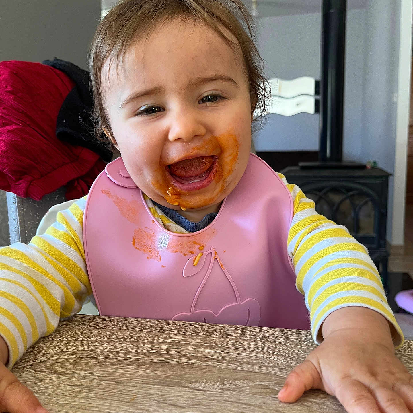 Adriana a rejoint le concours — aidez-le/la à gagner de superbes lots ! baby, bib, child, clothing, cute, face, food_stains, happy, highchair, home, indoor, messy_face, person, portrait, reaching, smiling, table, toddler, wooden_table, yellow_striped_shirt