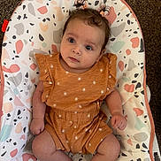 Ashly joined the competition — help win amazing prizes! baby, infant, child, baby_seat, patterned_fabric, orange_clothing, pony_tail, cute, wide_eyes, indoor, carpet, sitting, small_hands, small_feet, curly_hair, comfortable, bright_colors, soft_lighting, portrait, adorable