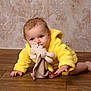 baby, child, yellow_jacket, plush_toy, crawling, wooden_floor, indoor, cute, infant, soft_toy, person, face, blue_eyes, hand, foot, wallpaper, cozy, warm_colors, portrait, expression