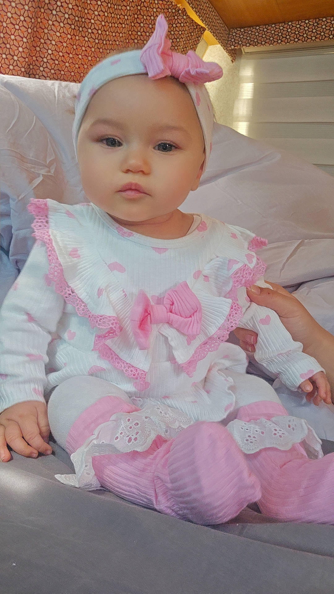 Nayra a rejoint le concours — aidez-le/la à gagner de superbes lots ! baby, bed, blanket, calm, child, clothing, cute, decor, frills, headband, indoor, infant, patterned_wall, person, pink, portrait, seated, socks, soft_lighting, white