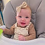 Aurora is registered to the contest to win money with this photo: apparel, baby, baby_toy, bow, child, clothing, cute, expression, face, happy, headband, high_chair, indoor, infant, person, portrait, seat, sitting, smile, young