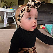 Aurora is registered to the contest to win money with this photo: baby, infant, headband, leopard_print, black_clothing, sitting, carpet, living_room, blue_eyes, cute, child, toddler, curious, indoors, soft_lighting, furniture, play_area, floor, young_child, portrait