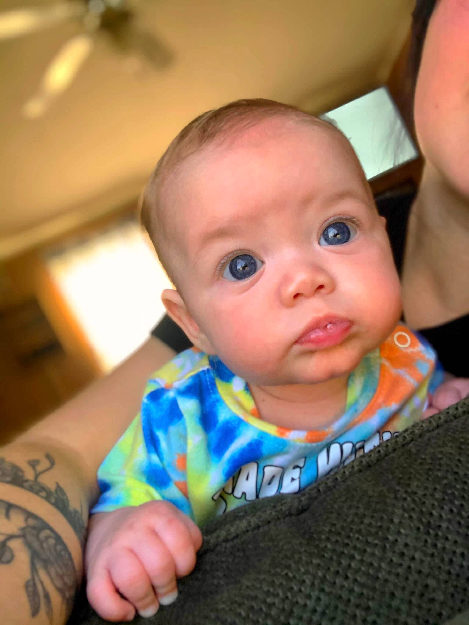 Lennon is registered to the contest to win money with this photo: baby, baby_toddler_clothing, ceiling_fan, cheek, chin, comfort, eye, eyebrow, finger, hairstyle, hand, happy, head, iris, joint, mouth, muscle, nose, person, skin