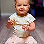 Sofia is registered to the contest to win money with this photo: toddler, child, baby, sitting, floor, snack, smile, face, clothing, striped_shirt, patterned_pants, indoors, wood_floor, cute, young_child, person, hand, toy, pink, happy