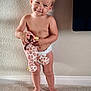 toddler, child, baby, diaper, barefoot, plush_toy, giraffe_toy, carpet, standing, smiling, cute, indoor, wall, texture, light, person, young_child, innocent, happy, playful