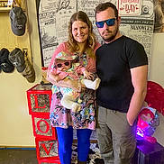 Amyra joined the competition — help win amazing prizes! baby, adult_female, adult_male, sunglasses, sun_hat, valentines_sign, love_blocks, floral_dress, blue_tights, boots, indoor, family, portrait, holding_baby, hats_on_wall, decor, wood_floor, smile, casual_clothing, photo_booth