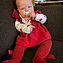 Amyra is registered to the contest to win money with this photo: baby, infant, child, pacifier, sofa, couch, red_dress, red_tights, sitting, indoors, furniture, background_papers, heart_pattern, portrait, hand, legs, pacifier_clip, ruffled_sleeves, fabric_texture, cozy